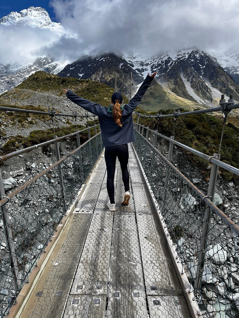 AIFS-ugc-au-pair-neuseeland-Brücke-Person-Berge-Wolken-Steine-rw