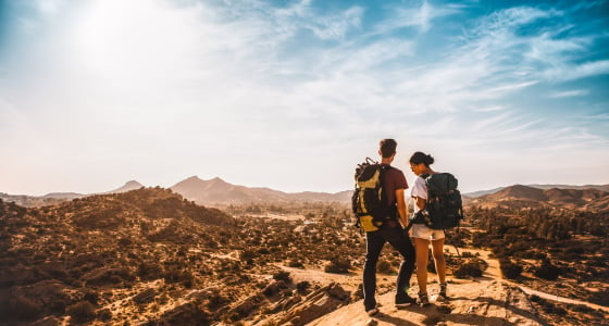 AIFS Australien: Personen erkunden das Outback beim Wandern mit Rucksack – Entdecke abenteuerliche Reisen mit AIFS Adventure Trips.