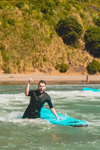 aifs-surfcamp-neuseeland-person-surfen-meer-küste-surfboard