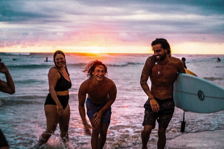 Fröhliche Surfer sammeln sich nach einer Surflektion am Strand von Sri Lanka.
