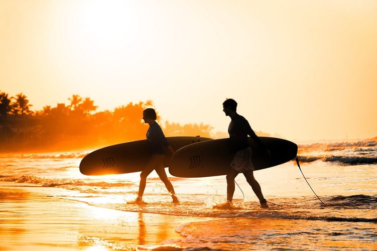 Wunderschöner Sonnenuntergang über dem Kabalana Beach in Sri Lanka mit Silhouetten von Menschen mit Surfbrettern.