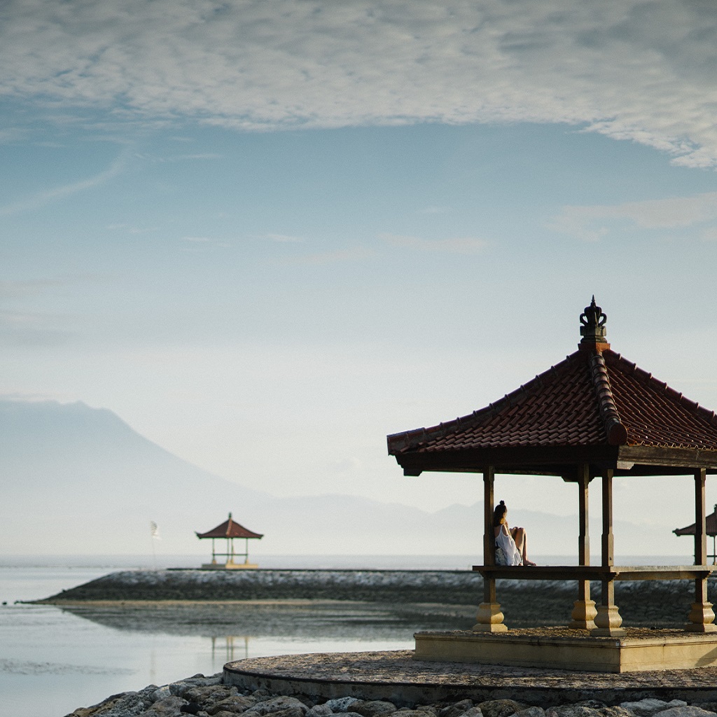  AIFS Bali Adventure Trips: Entdecke intensiv und authentisch Balis faszinierende Schönheit  am Strand mit Bergblick, Wasser und Pavillon.